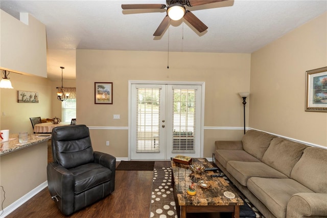 living area featuring french doors, baseboards, ceiling fan with notable chandelier, and dark wood-style floors