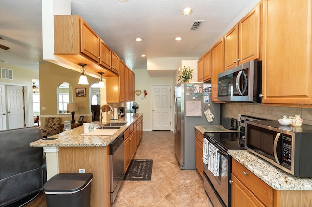 kitchen with light stone countertops, appliances with stainless steel finishes, a sink, a peninsula, and recessed lighting