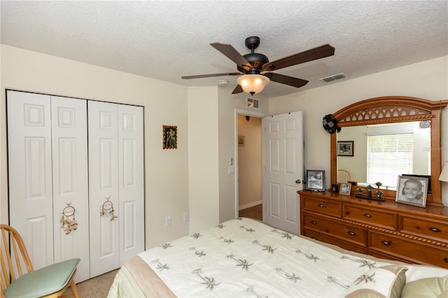 carpeted bedroom featuring a ceiling fan, a closet, a textured ceiling, and visible vents
