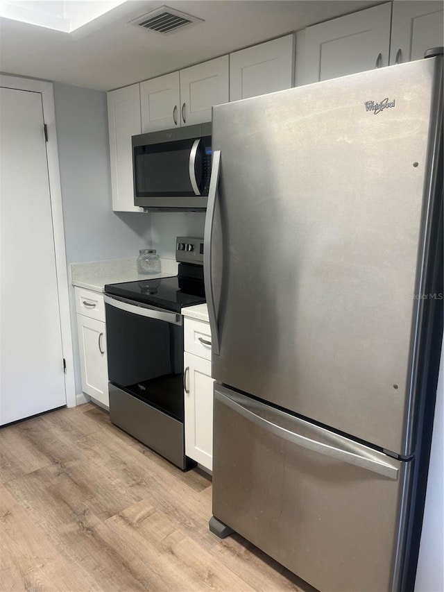 kitchen featuring visible vents, light wood-type flooring, light countertops, white cabinetry, and appliances with stainless steel finishes