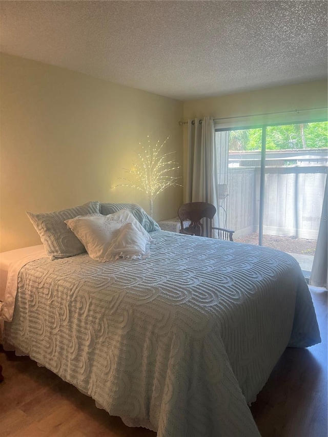 bedroom featuring a textured ceiling, access to exterior, and wood finished floors
