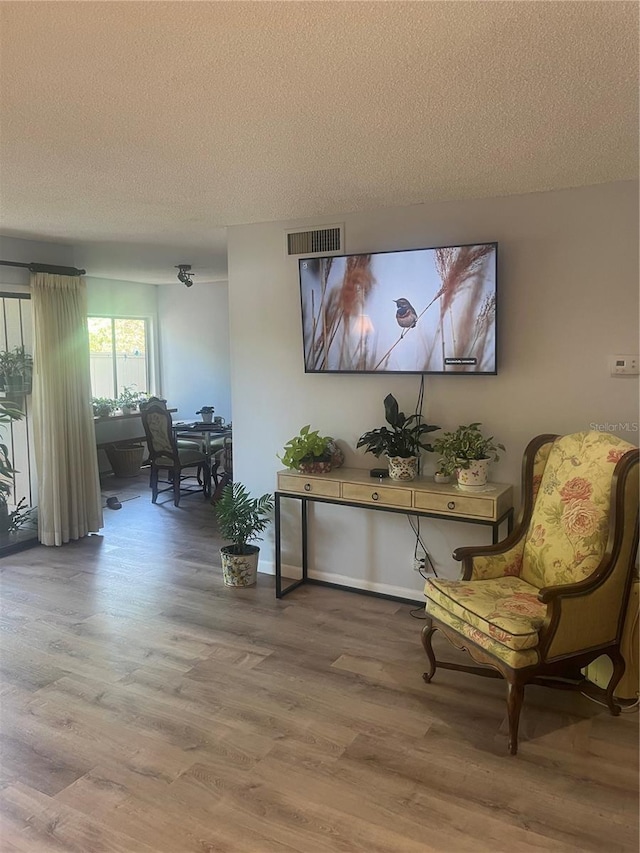 living area featuring a textured ceiling, wood finished floors, and visible vents