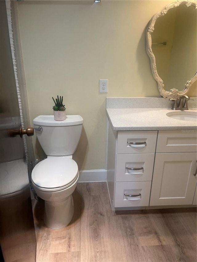 bathroom with toilet, baseboards, wood finished floors, and vanity
