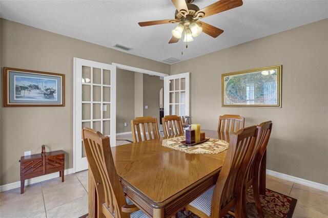 dining area with light tile patterned floors, baseboards, a ceiling fan, and visible vents