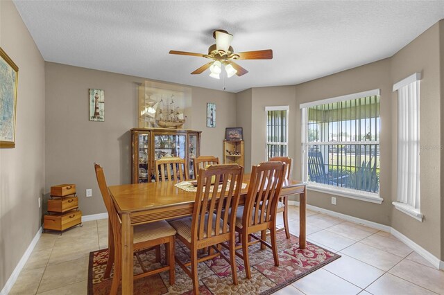 dining space with light tile patterned floors, baseboards, and a ceiling fan