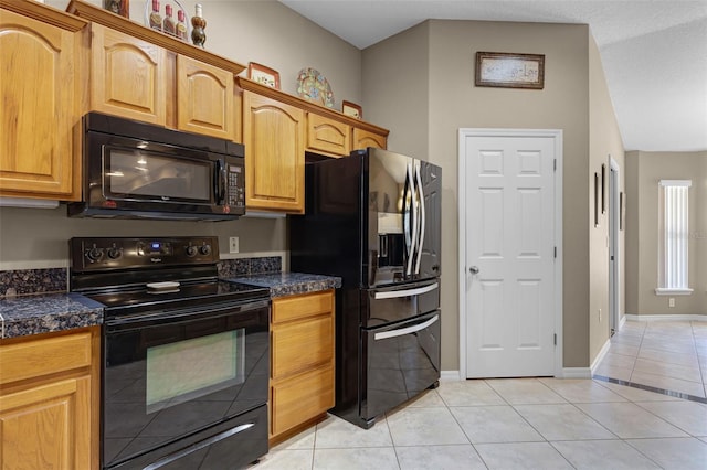 kitchen featuring baseboards, light tile patterned floors, and black appliances