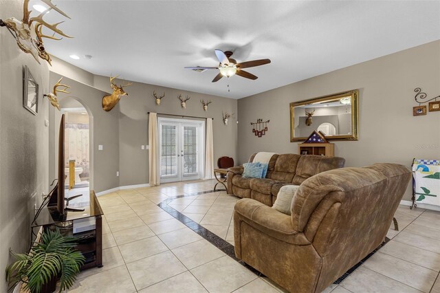 living room featuring baseboards, arched walkways, ceiling fan, and light tile patterned floors