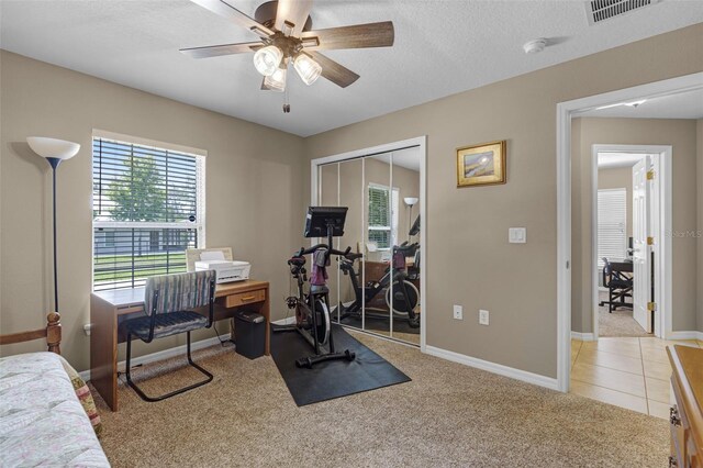 workout area with baseboards, visible vents, a ceiling fan, and light colored carpet