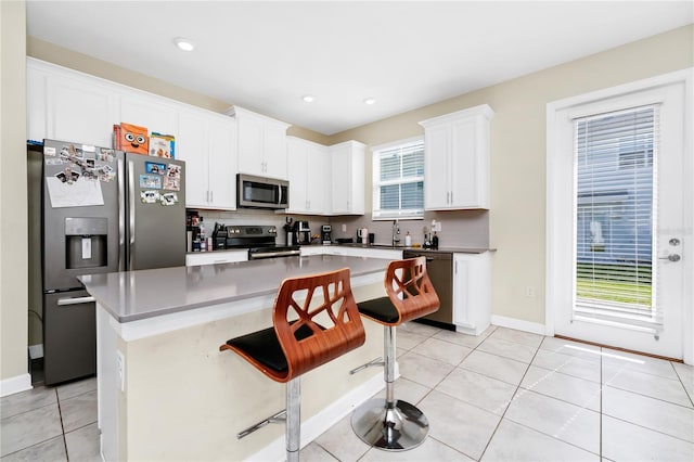 2919 Verse St, Kissimmee, FL 34746 - kitchen with light tile patterned flooring, appliances with stainless steel finishes, white cabinetry, backsplash, and a kitchen island