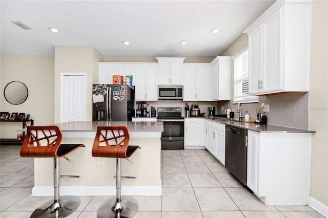 2919 Verse St, Kissimmee, FL 34746 - kitchen with visible vents, decorative backsplash, a kitchen breakfast bar, a sink, and stainless steel appliances