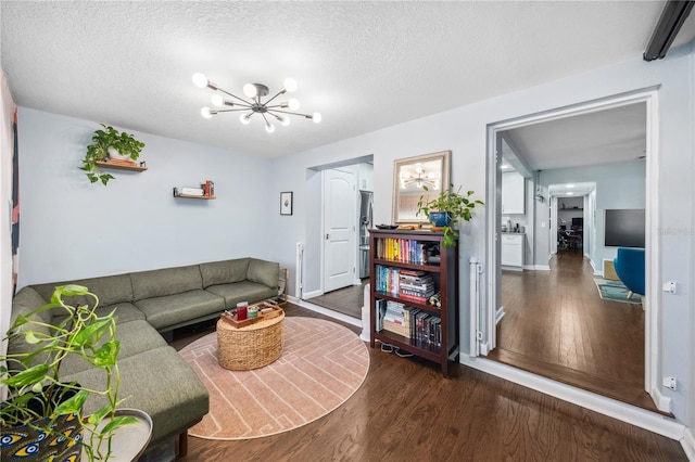 living area with a textured ceiling, baseboards, an inviting chandelier, and wood finished floors