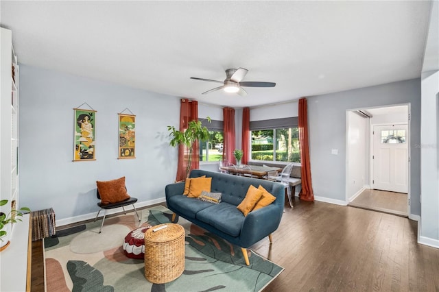 living area with baseboards, ceiling fan, wood finished floors, and a wealth of natural light