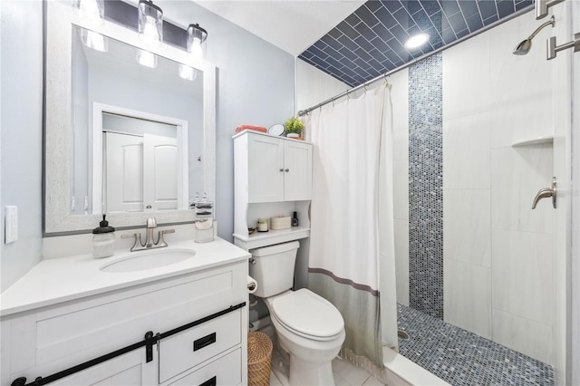 bathroom with toilet, a tile shower, and vanity