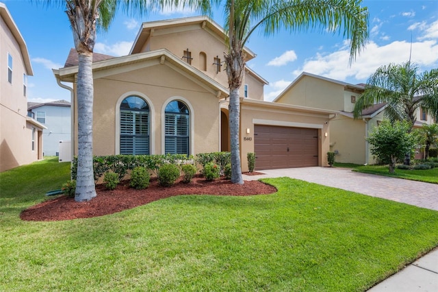 15443 Sugarcup Ct, Orlando, FL 32828 - mediterranean / spanish-style home with stucco siding, decorative driveway, an attached garage, and a front lawn