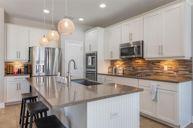 15443 Sugarcup Ct, Orlando, FL 32828 - kitchen with appliances with stainless steel finishes, light tile patterned flooring, backsplash, a breakfast bar area, and an island with sink