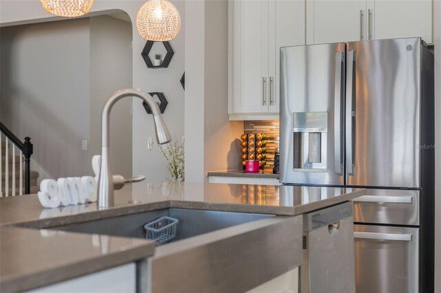 15443 Sugarcup Ct, Orlando, FL 32828 - kitchen with appliances with stainless steel finishes, a sink, white cabinetry, backsplash, and pendant lighting