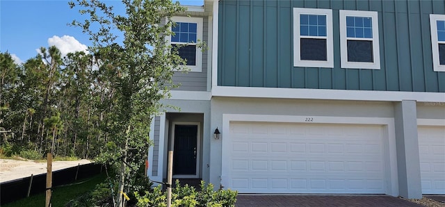 view of front of home featuring board and batten siding, decorative driveway, and a garage