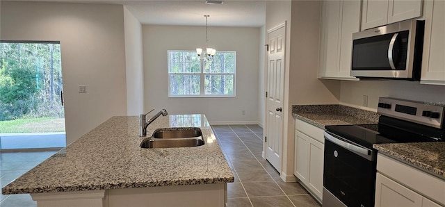kitchen with appliances with stainless steel finishes, a sink, a chandelier, stone countertops, and dark tile patterned floors