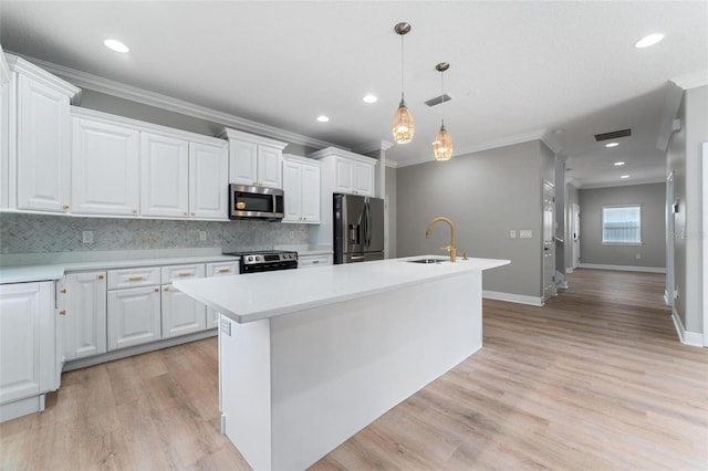 kitchen featuring a kitchen island with sink, backsplash, a sink, ornamental molding, and stainless steel appliances