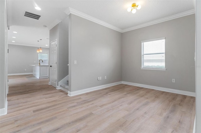 unfurnished room with crown molding, light wood finished floors, baseboards, visible vents, and stairway
