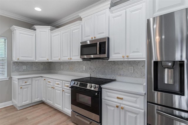 kitchen featuring crown molding, light countertops, light wood finished floors, stainless steel appliances, and white cabinetry