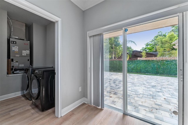laundry room with laundry area, washer and clothes dryer, light wood-style flooring, and a healthy amount of sunlight