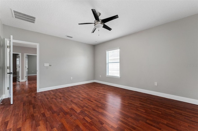 empty room featuring ceiling fan, visible vents, and dark wood finished floors