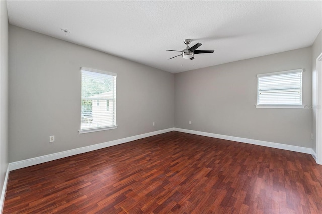 unfurnished room featuring a ceiling fan, baseboards, and dark wood finished floors