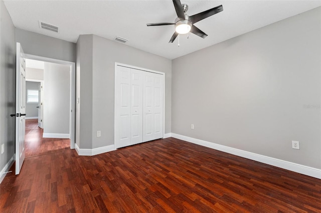 unfurnished bedroom featuring baseboards, visible vents, wood finished floors, and a closet