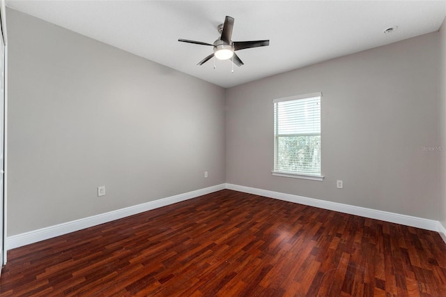 empty room featuring baseboards, a ceiling fan, and dark wood-style floors