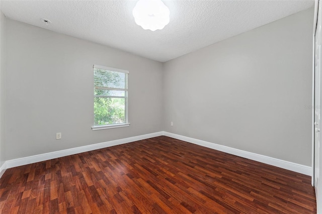 empty room featuring baseboards, dark wood finished floors, and a textured ceiling