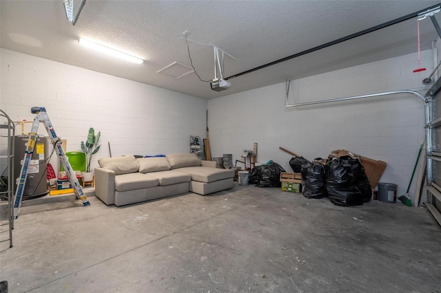 garage featuring water heater, concrete block wall, and a garage door opener