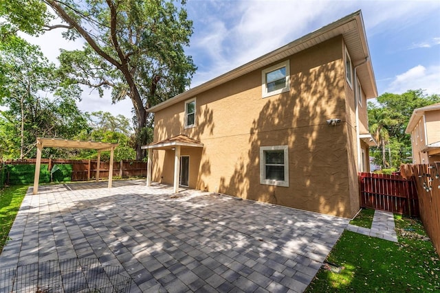 rear view of property featuring a patio, a fenced backyard, stucco siding, and a pergola