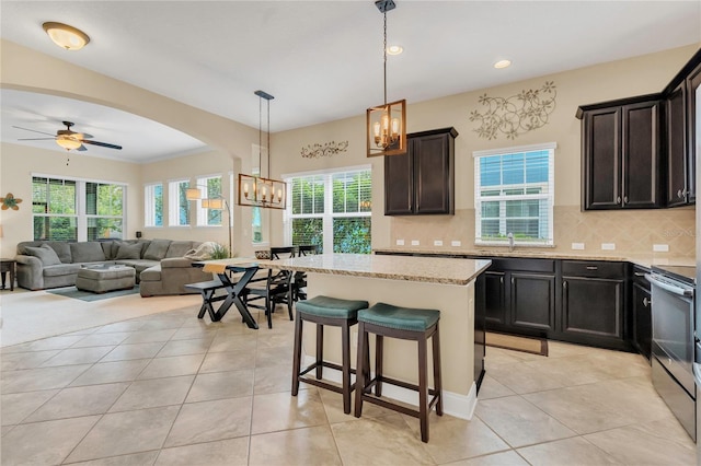 kitchen with light stone countertops, tasteful backsplash, light tile patterned floors, and stainless steel range with electric stovetop