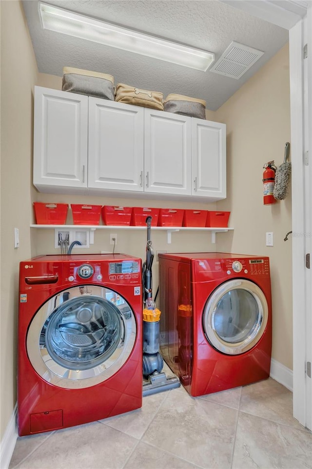 clothes washing area featuring independent washer and dryer, visible vents, cabinet space, light tile patterned floors, and baseboards