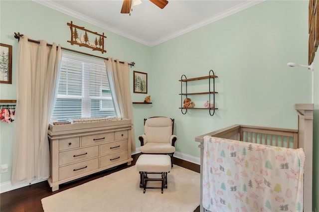 bedroom featuring a nursery area, ornamental molding, a ceiling fan, baseboards, and dark wood-style floors