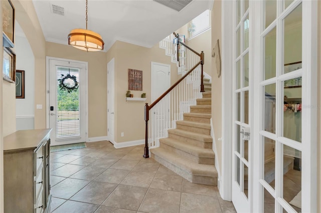foyer entrance with light tile patterned floors, french doors, stairs, and visible vents