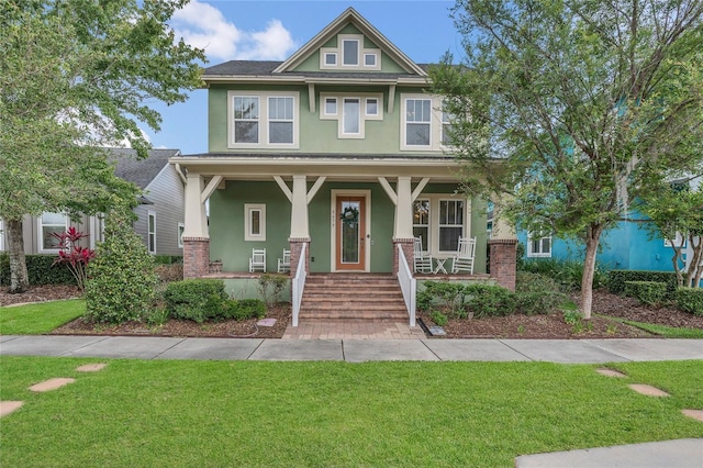 view of front of home with stucco siding, a porch, and a front yard