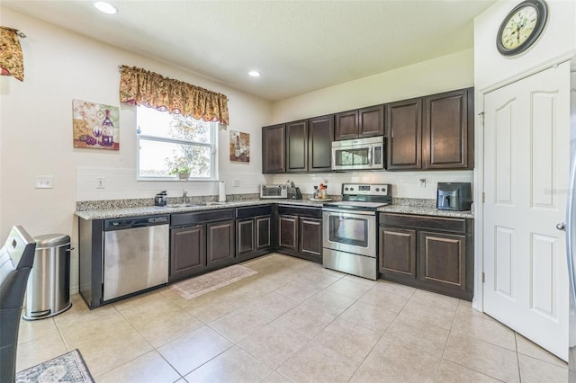 2815 Shelburne Way, Saint Cloud, FL 34772 - kitchen featuring dark brown cabinets, a sink, light tile patterned floors, stainless steel appliances, and recessed lighting