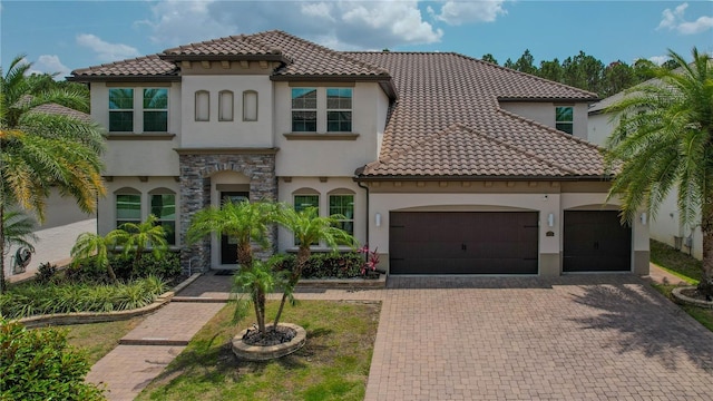 mediterranean / spanish home with stucco siding, decorative driveway, a garage, and a tile roof