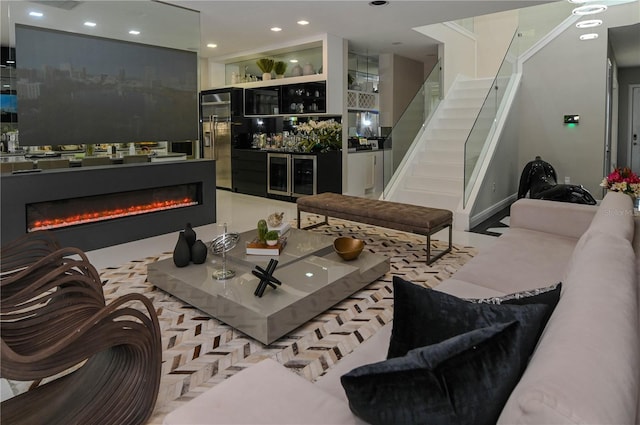 living area featuring stairway, a glass covered fireplace, recessed lighting, a dry bar, and baseboards