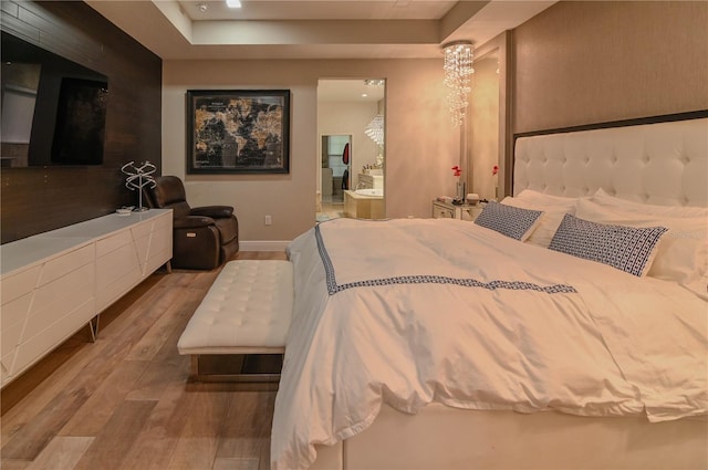 bedroom with wood finished floors, a tray ceiling, and baseboards