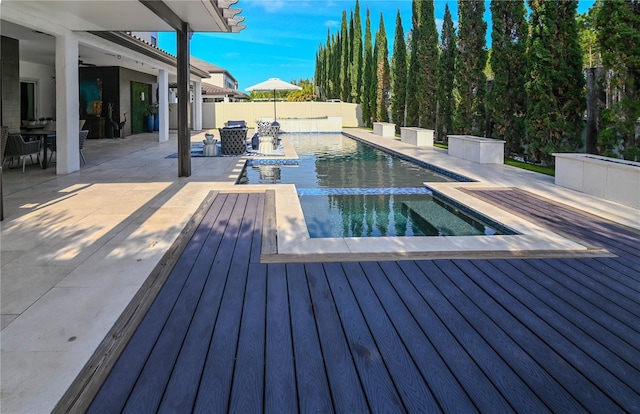 view of swimming pool featuring a wooden deck, an in-ground hot tub, outdoor dining area, a fenced backyard, and a patio