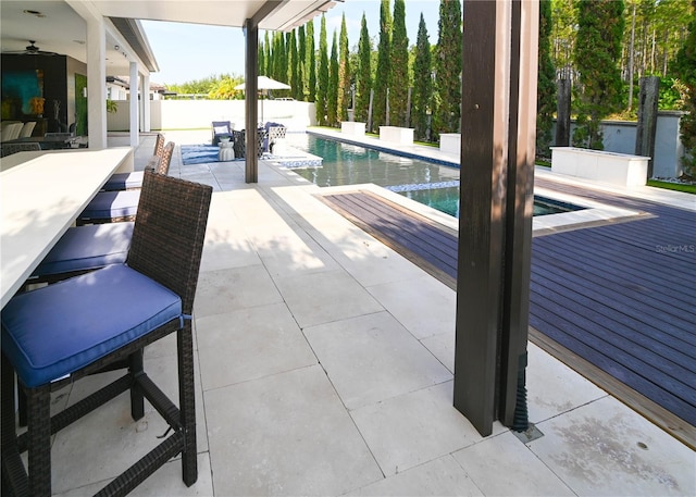 view of patio / terrace with an outdoor pool, a ceiling fan, and a deck