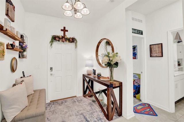 foyer with a chandelier, baseboards, visible vents, and light tile patterned floors