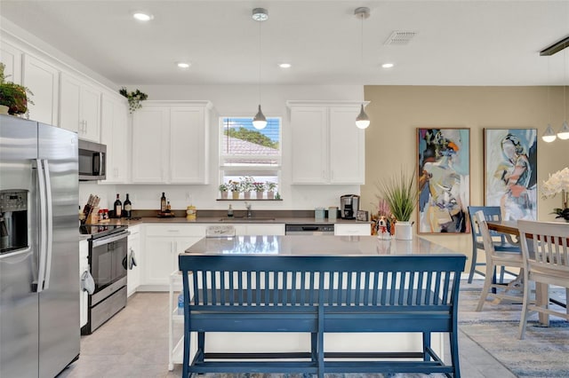 kitchen featuring visible vents, appliances with stainless steel finishes, hanging light fixtures, a sink, and white cabinets