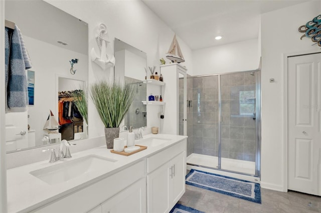 bathroom featuring double vanity, a sink, tile patterned floors, and a stall shower