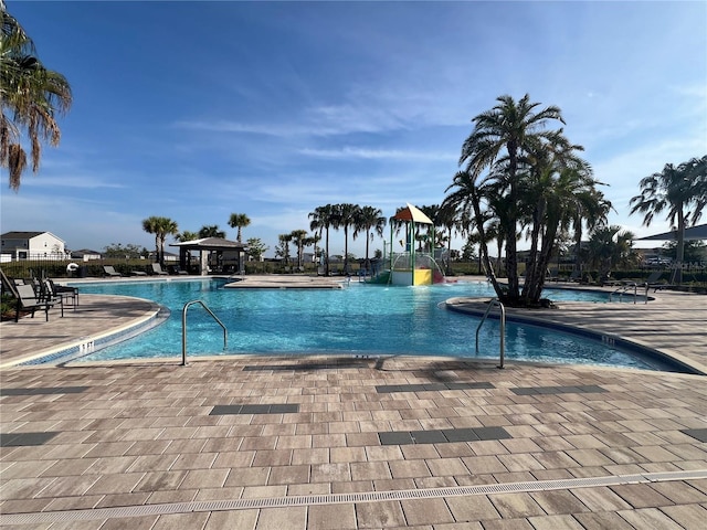 community pool featuring a water slide, a gazebo, and a patio area