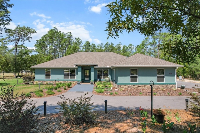 ranch-style home with a shingled roof and stucco siding