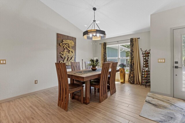 dining room with an inviting chandelier, light wood-style flooring, and lofted ceiling
